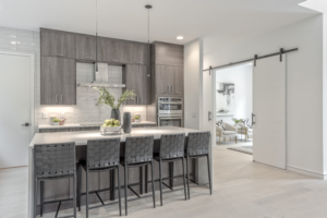 A kitchen with grey cabinets and white walls.