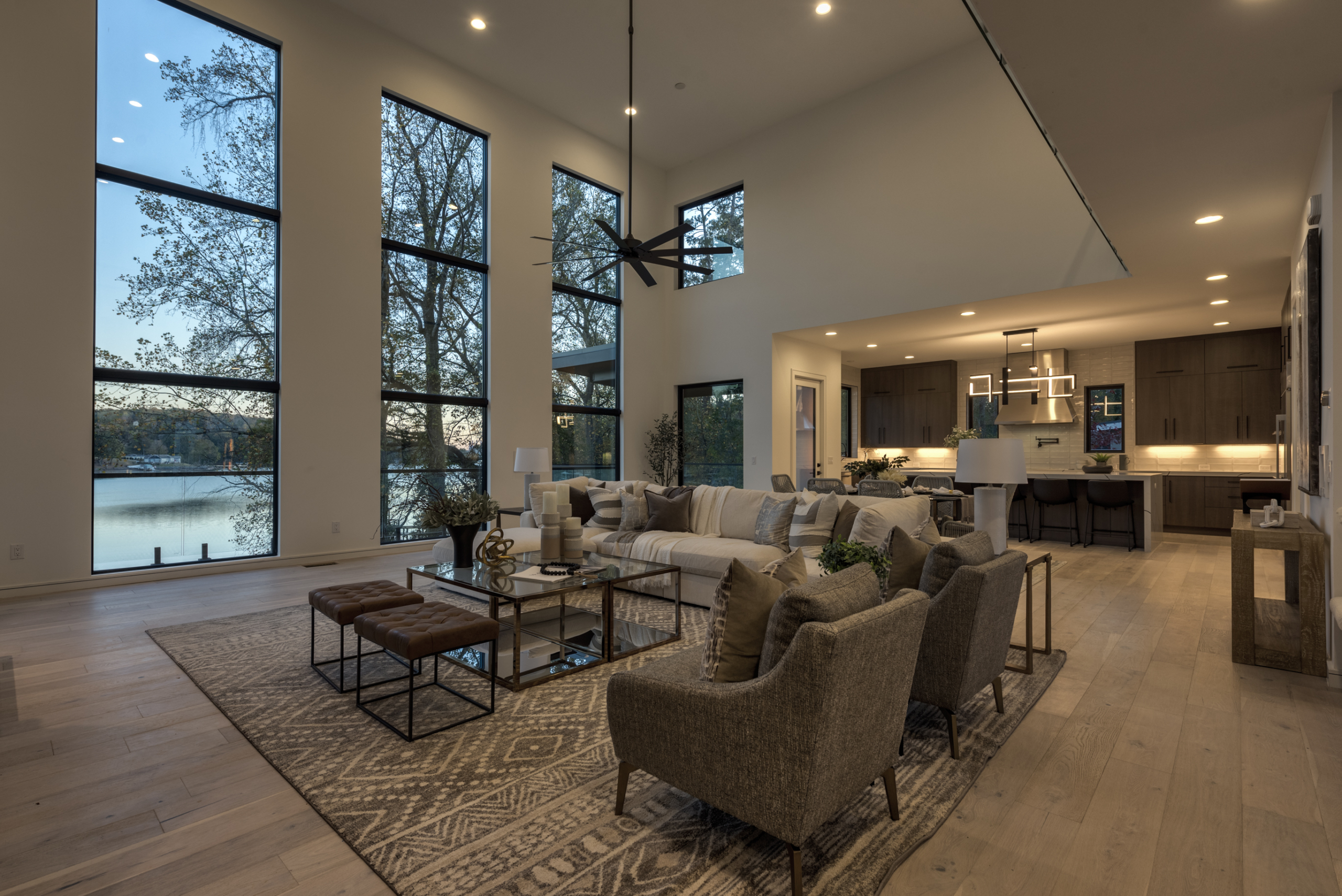 Modern contemporary living room with three huge floor to ceiling windows and open floor plan into kitchen