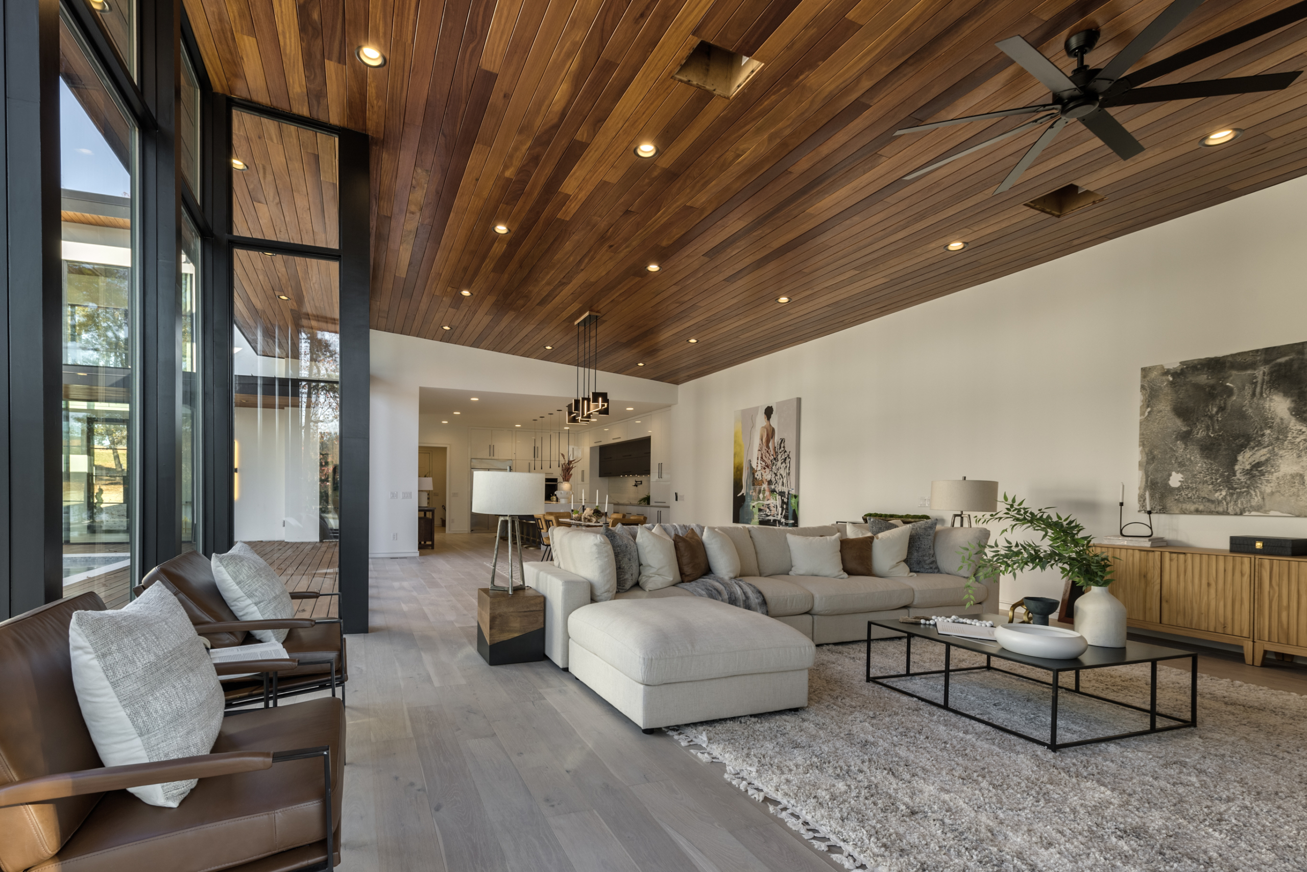 A living room with wood ceiling and white furniture.