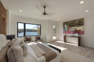 A bedroom with a large window and a view of the water.