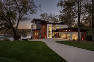 A large modern home with a lake in the background.