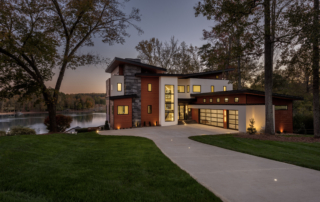 A large modern home with a lake in the background.