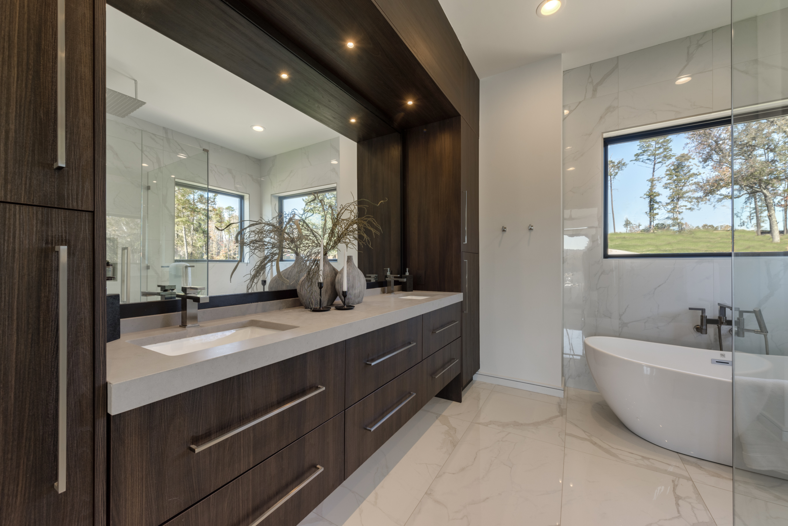 Modern bedroom bathroom with custom large floor to ceiling double vanity with dark wood and free standing tub