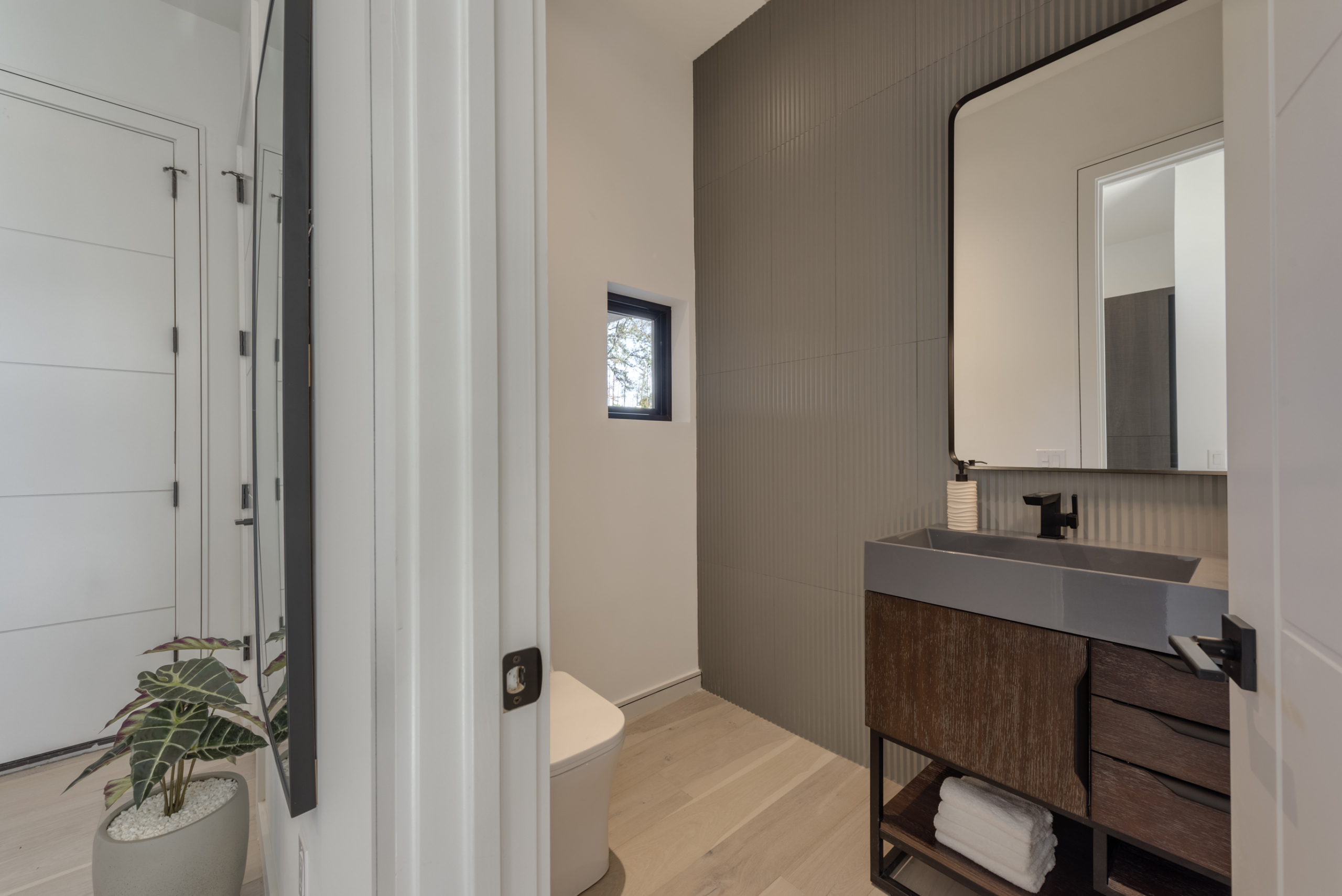 Modern Half bathroom with gray and dark wood vanity and detailed gray textured wavy wall