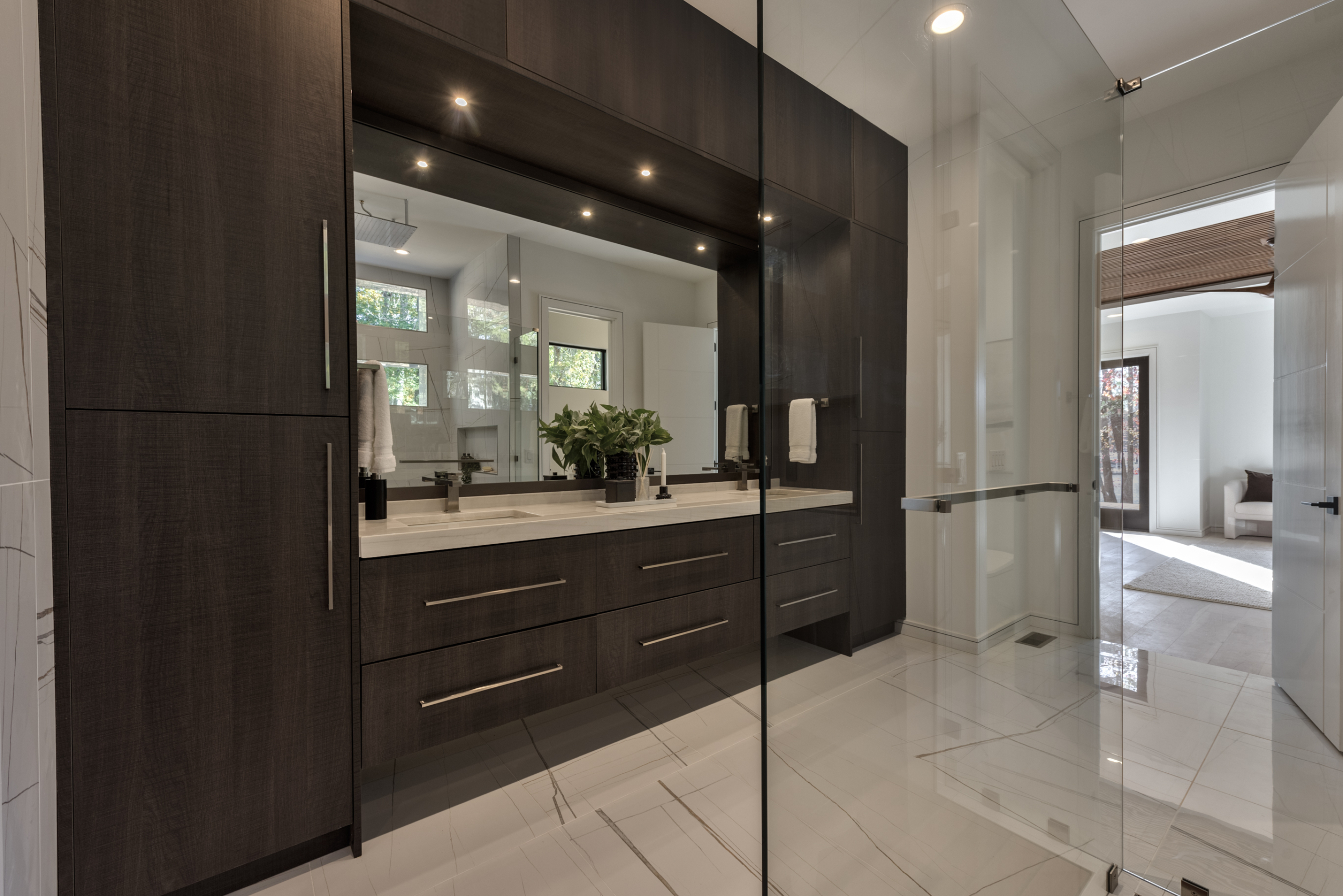 A bathroom with a large mirror and a glass shower door.