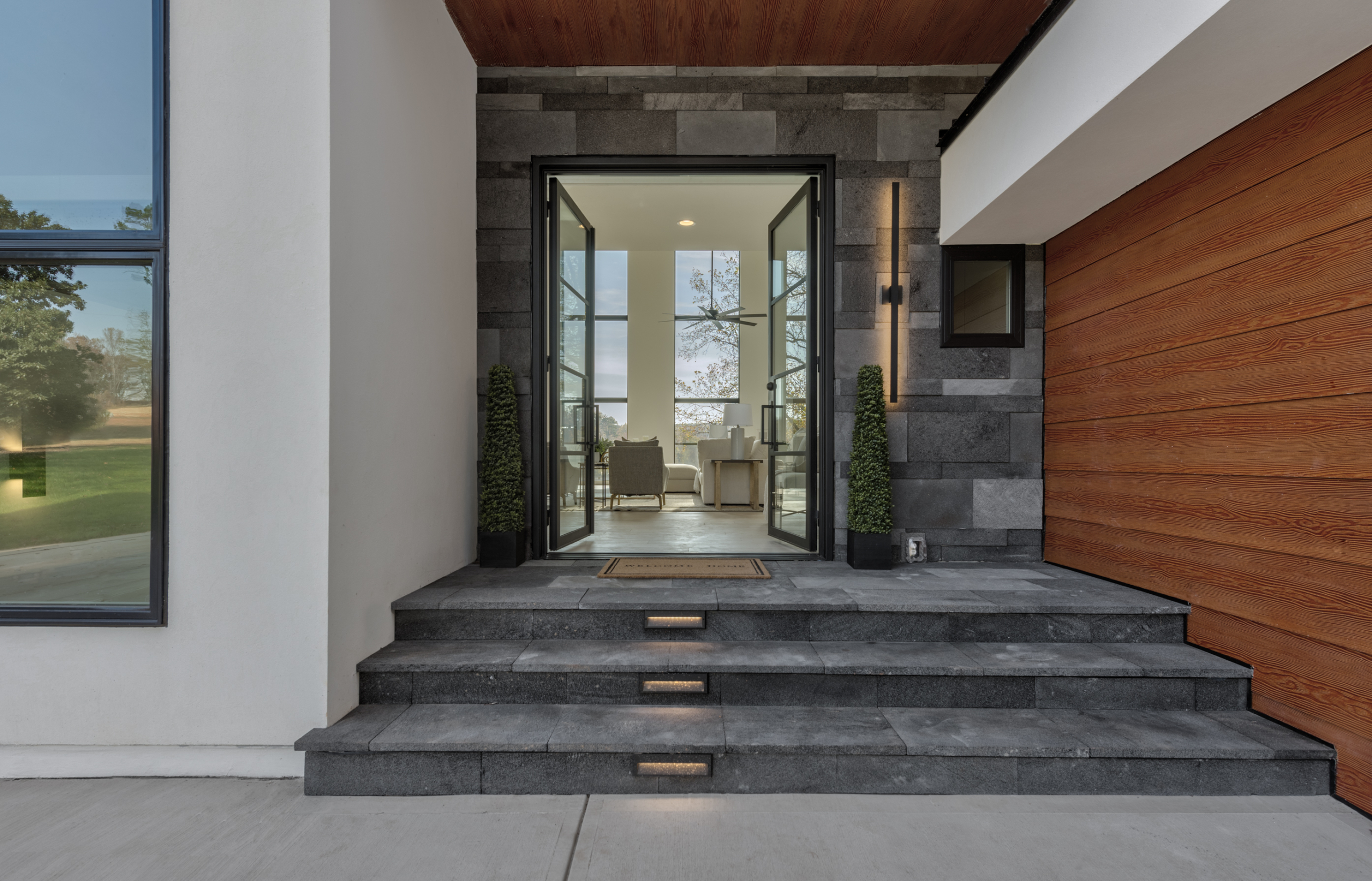 6’ wide x 8’ tall wrought iron and glass modern French front door with lava stone wall and custom stair lighting