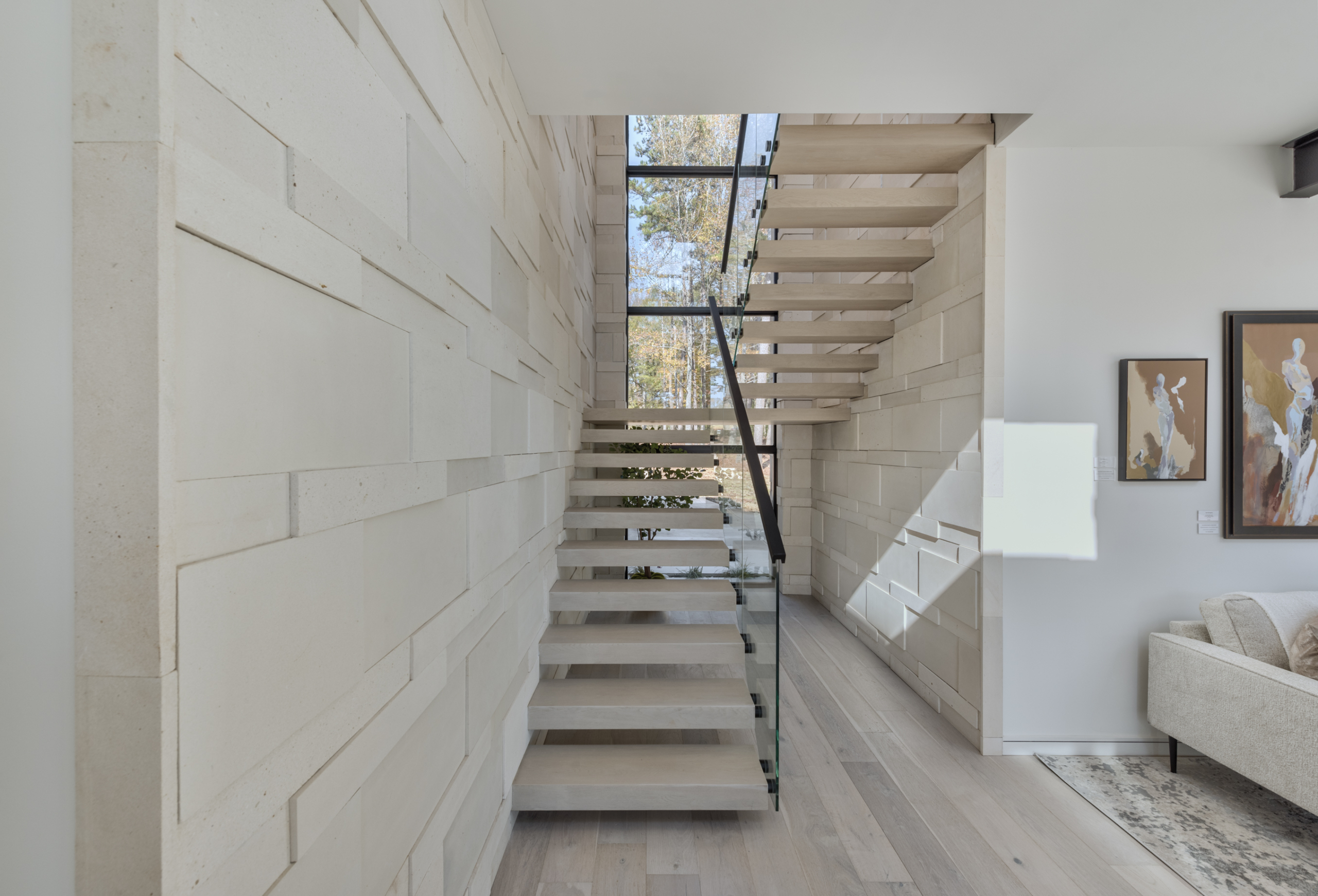 A white staircase with glass railing and wood steps.