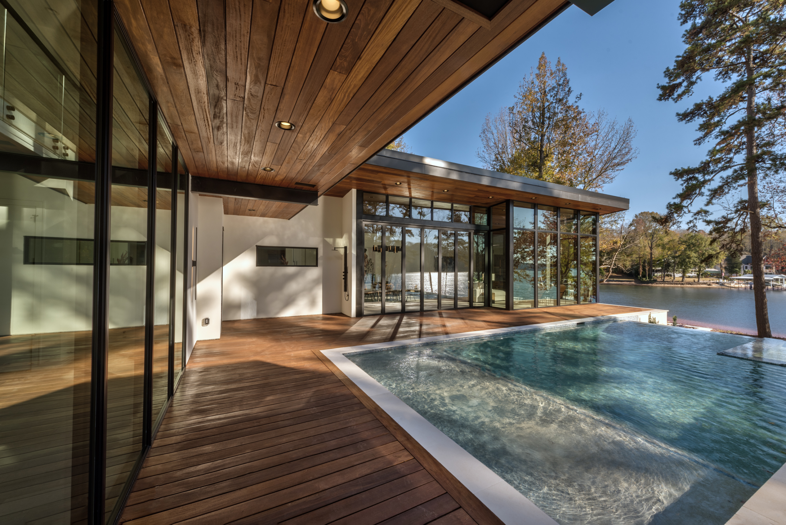 A pool with a wooden deck and a large window.