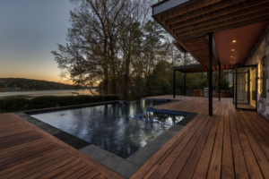A pool with an outdoor deck and trees in the background.