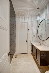 A bathroom with a sink, mirror and door.