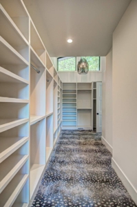 A long hallway with many shelves and a window.