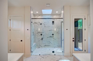 A large glass shower with a white marble floor.