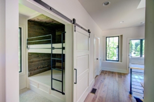 A room with two bunk beds and sliding barn door.