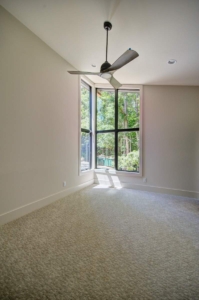 A room with a ceiling fan and large window.