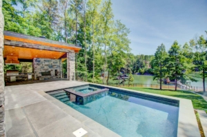 A pool with a fire pit and a large stone wall.