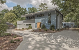 A large modern house with trees in the background.