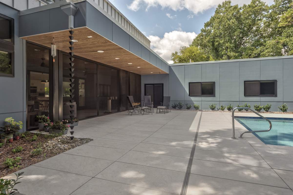 Modern exterior with pool and concrete, rain chains, overhang with metal roof and wood ceiling