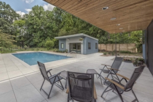 A patio with chairs and tables near the pool.