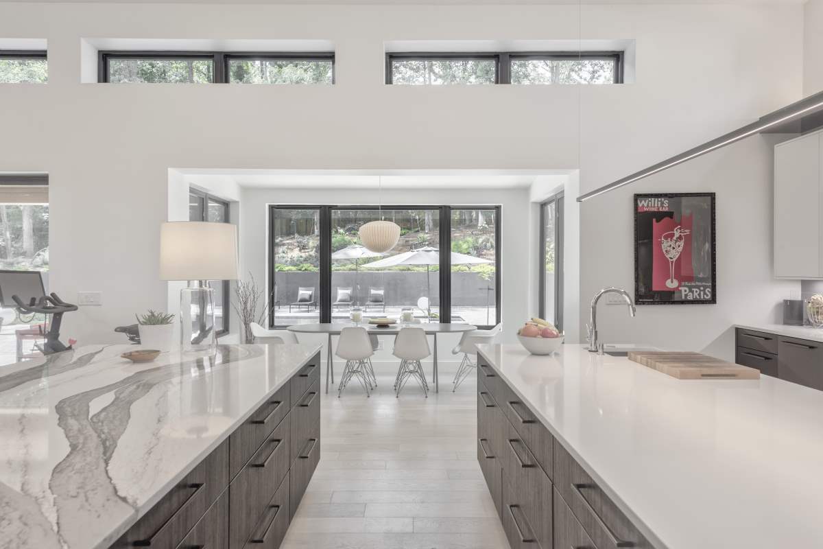 A large kitchen with white counters and a dining room.