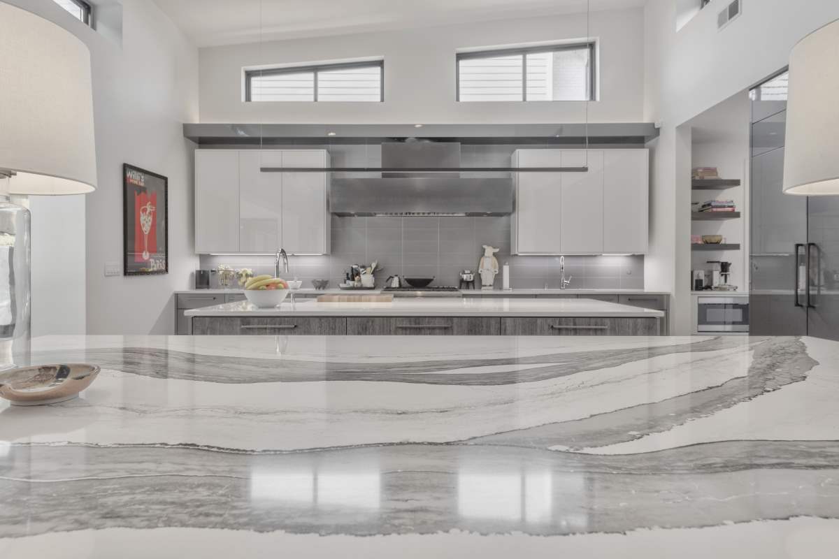 A kitchen with marble counter tops and stainless steel appliances.