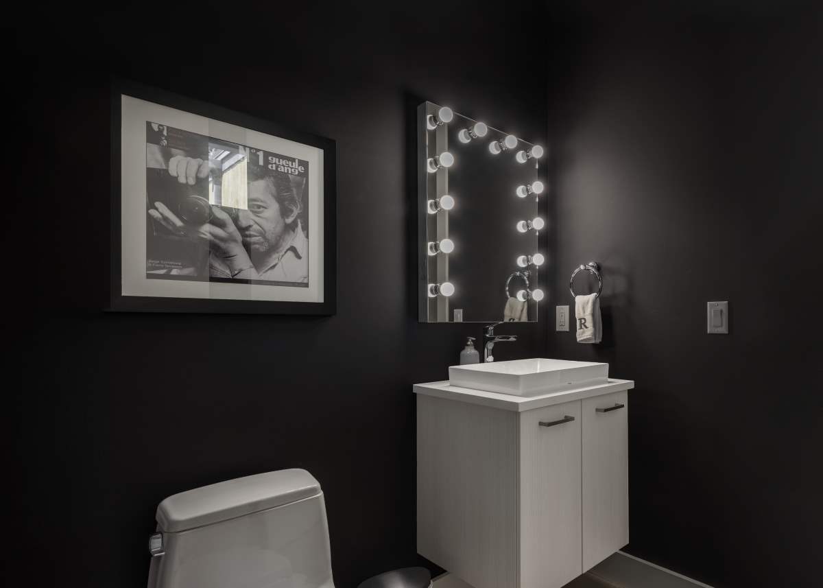 A bathroom with black walls and white fixtures.