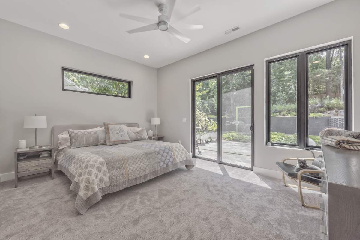 A bedroom with a bed, table and windows.