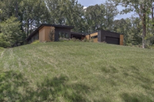 A house on the side of a hill with trees in the background.