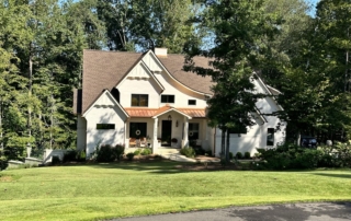 A large white house sitting on top of a green field.