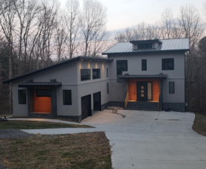A large gray house with orange doors and windows.