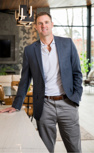 A man in a suit standing next to a table.