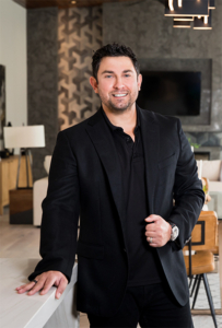 A man in black jacket standing next to a wall.