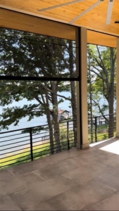 A view of trees and water from the outside of recessed shades.