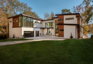 A large modern house with a green lawn.