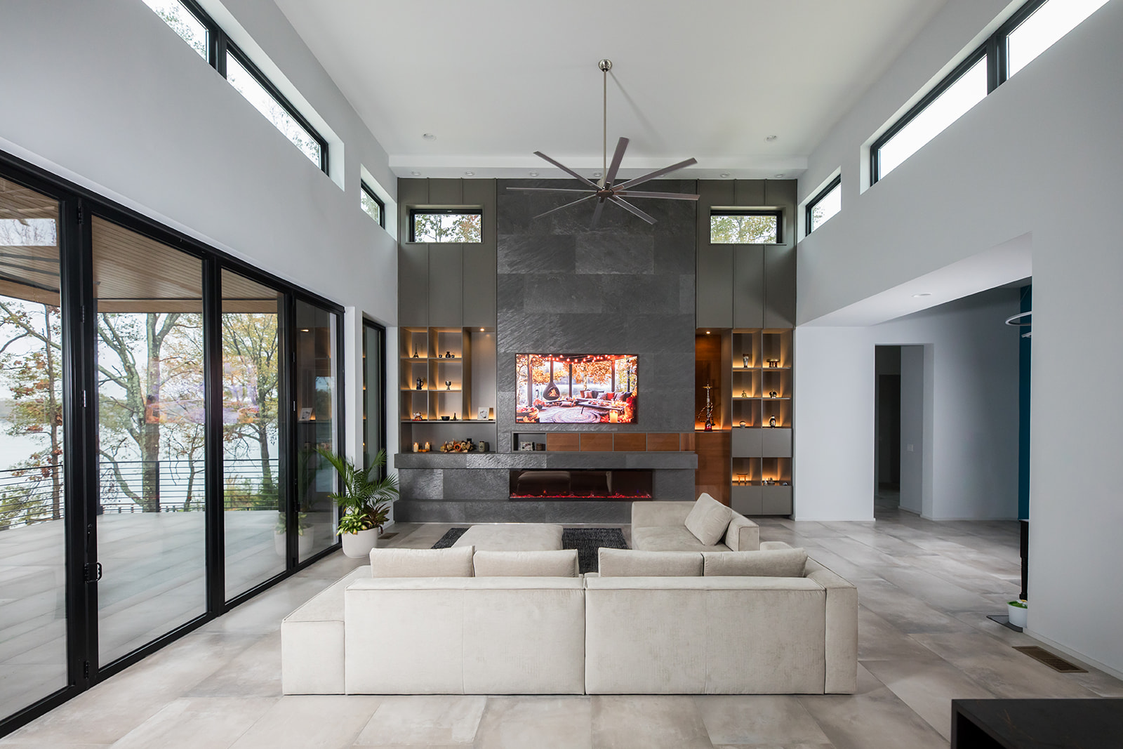 Modern gray slate living room with electric fire place, natural light, and folding glass doors.