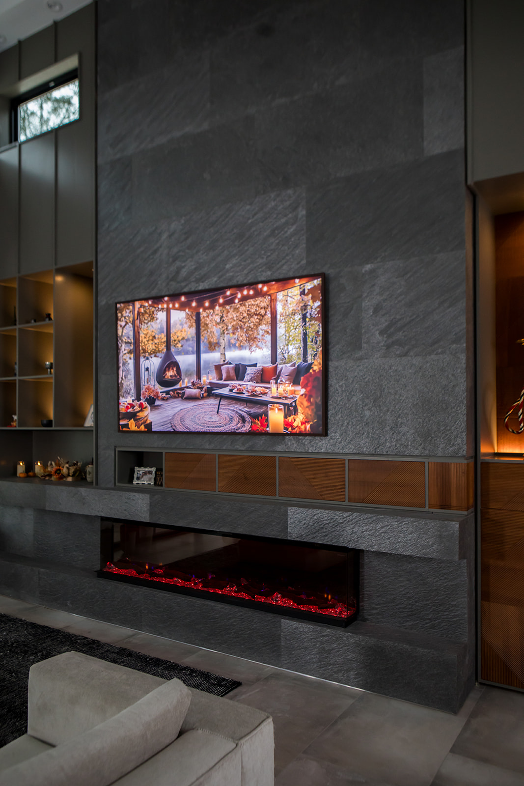 Modern gray slate living room with electric fire place, natural light, and folding glass doors.