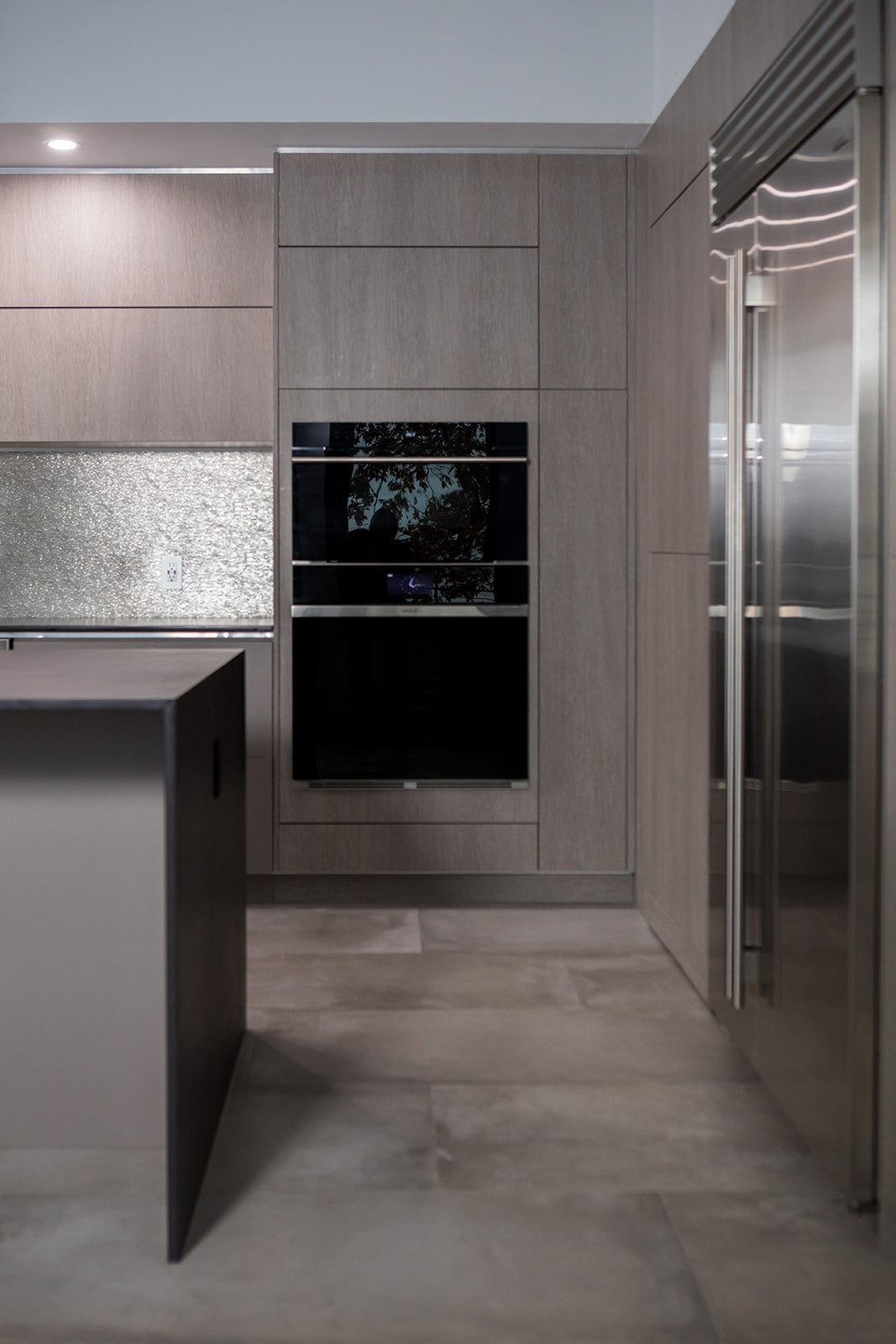 Modern gray slate minimalist kitchen with waterfall countertop and stainless steel hardware