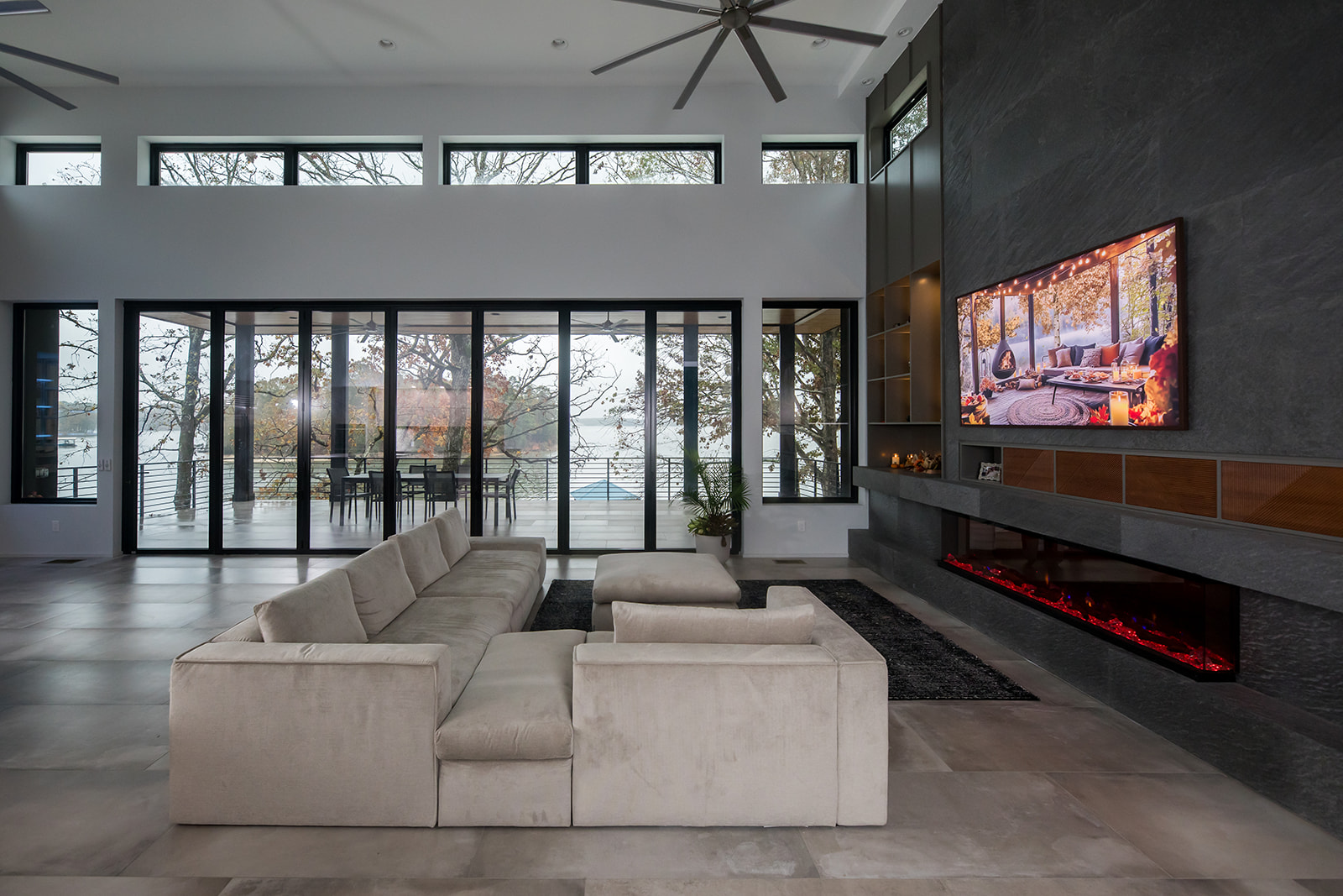 Modern gray slate living room with electric fire place, natural light, and folding glass doors.