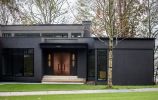 Artistic Contractors black modern home with rose gold front doors