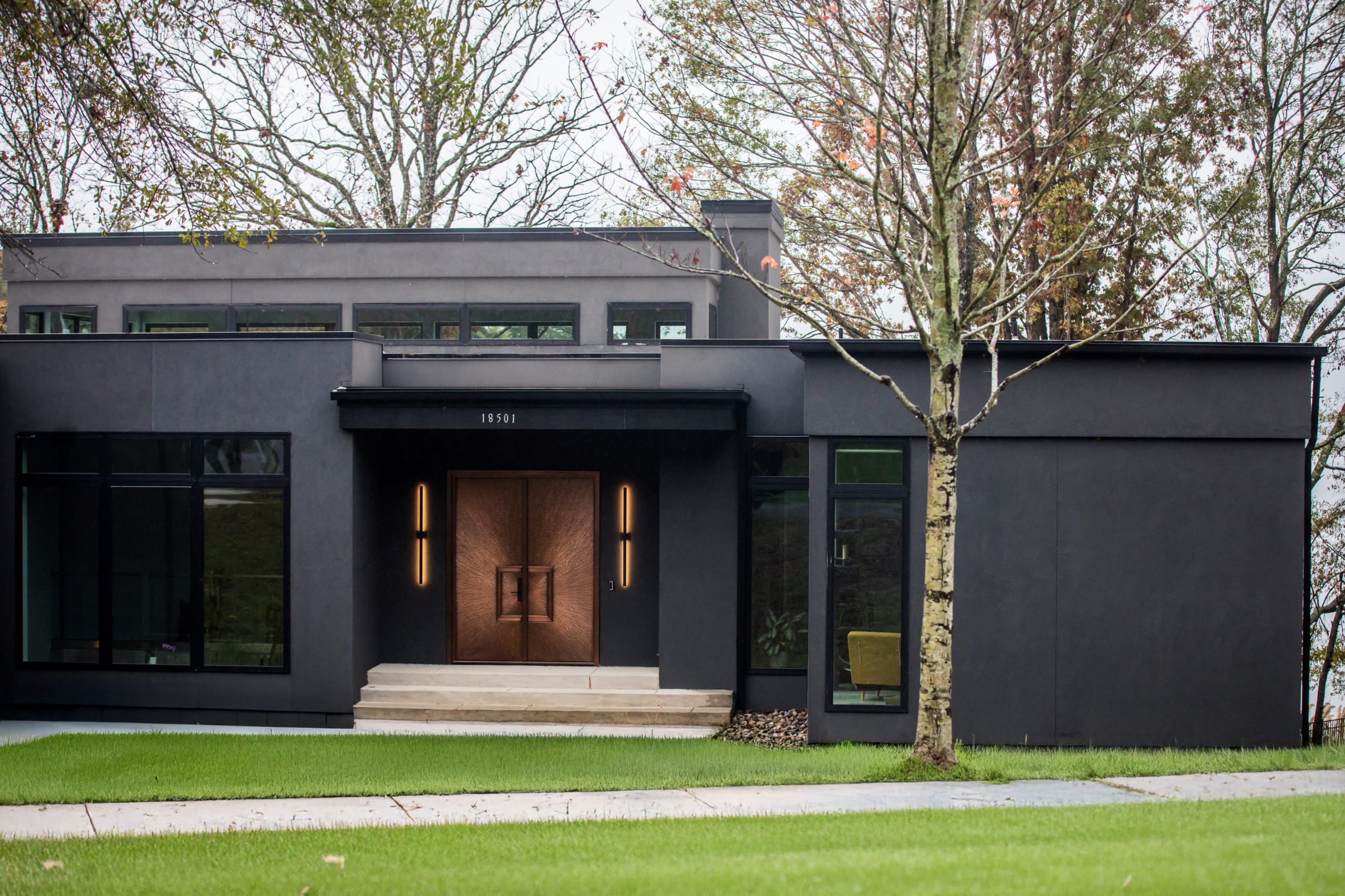 Artistic Contractors black modern home with rose gold front doors