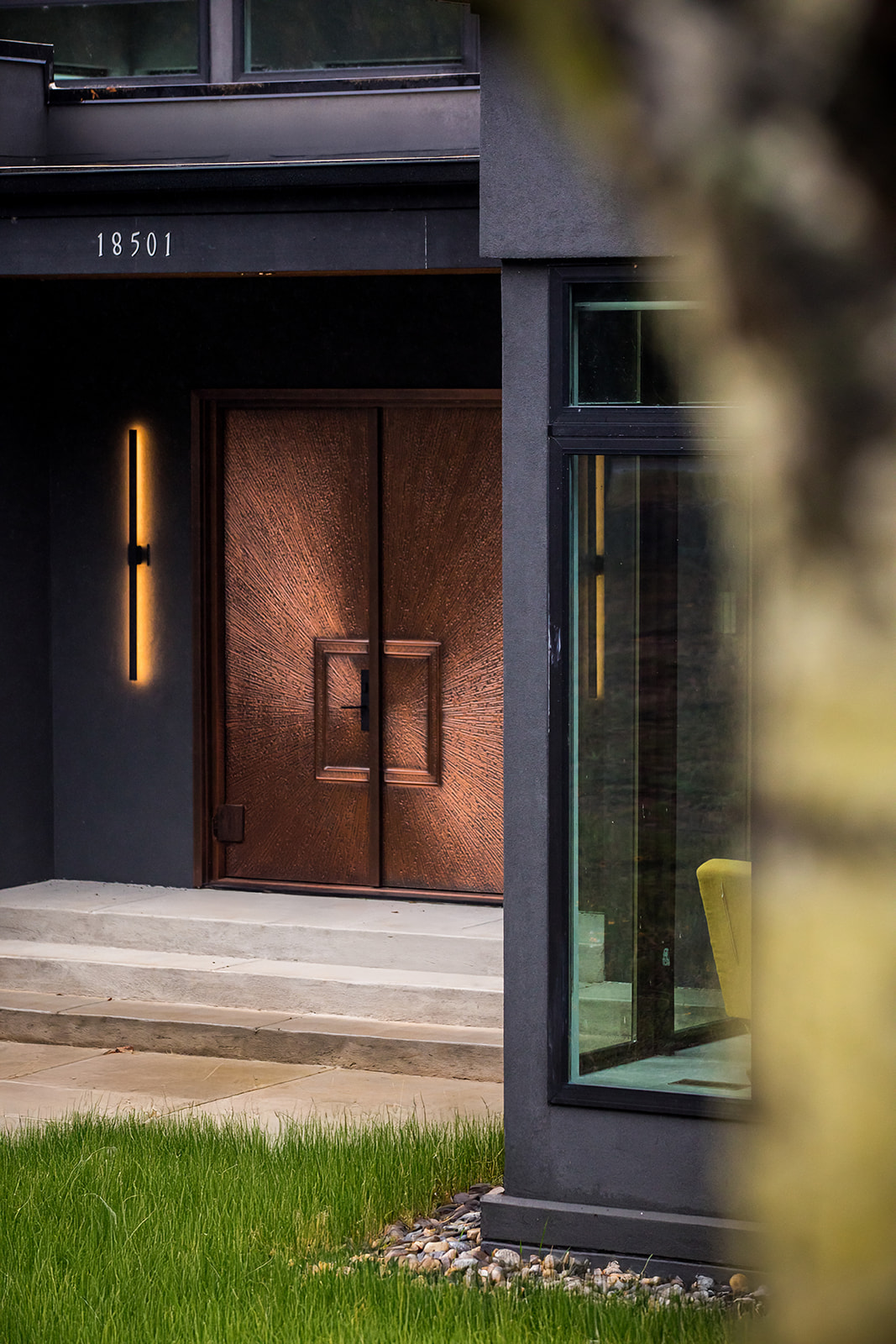 Artistic Contractors black modern home with rose gold front doors and exterior light fixture