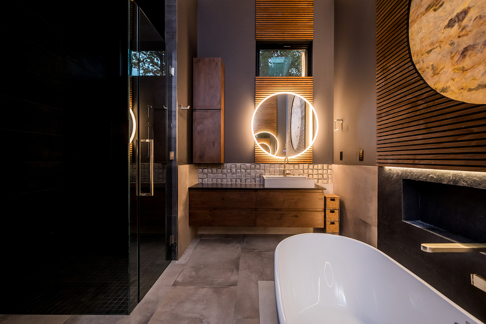 Modern bathroom with freestanding tub and wall marble stone sun moon and wood detail and backlit circle mirror