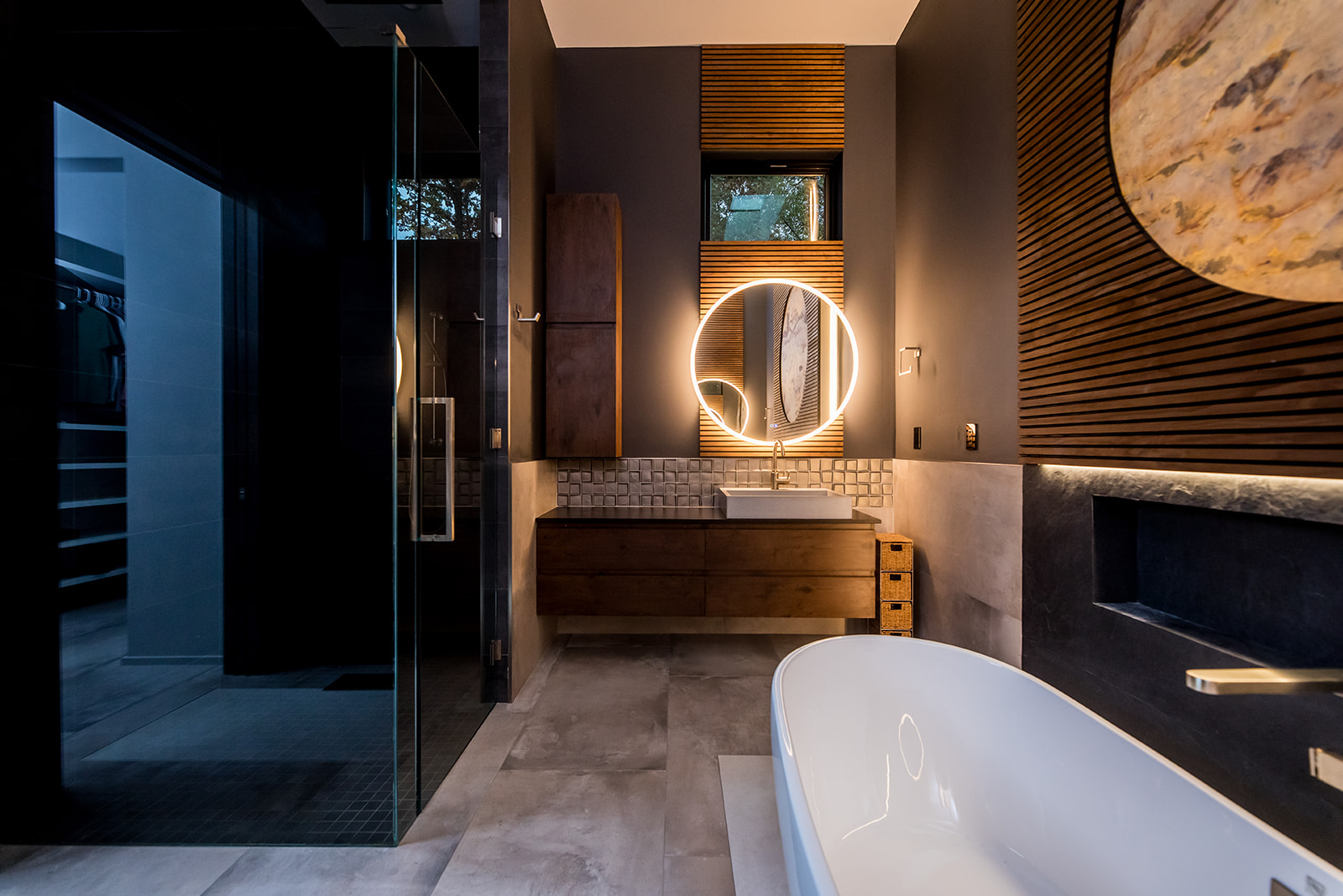 Modern bathroom with freestanding tub and wall marble stone sun moon and wood detail and backlit circle mirror