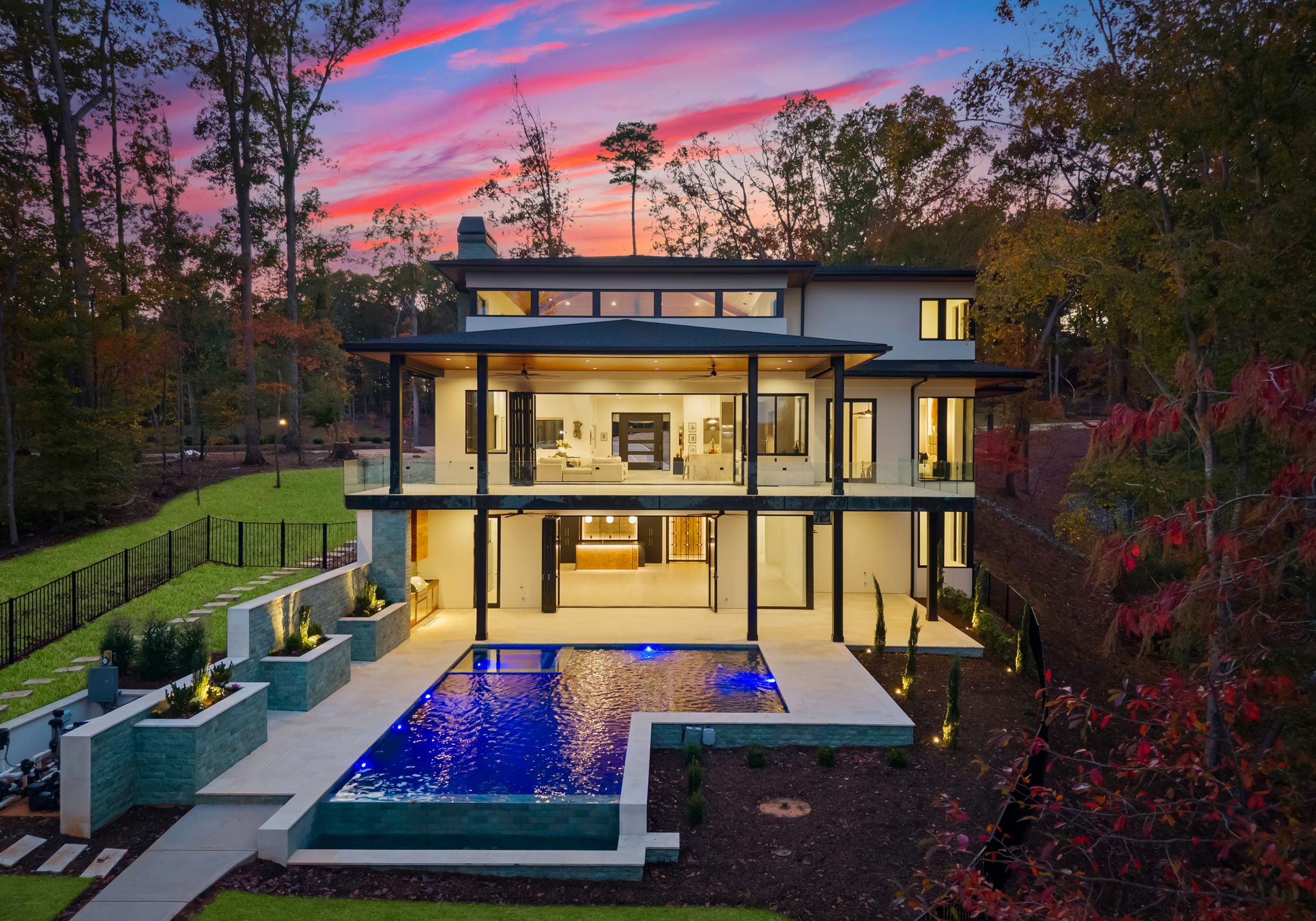 Modern luxury custom home with illuminated pool at twilight in Charlotte, North Carolina – built by Artistic Contractors